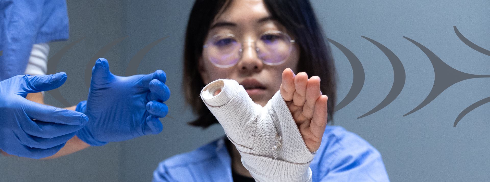 Young person with bandaged hand with hands of staff member supporting them.