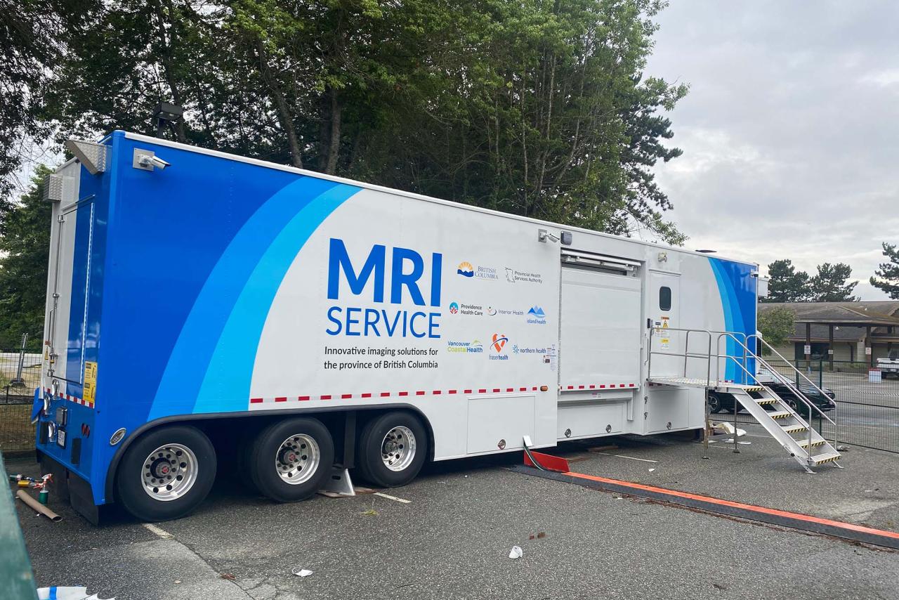 A large trailer in a parking lot that contains a mobile MRI machine
