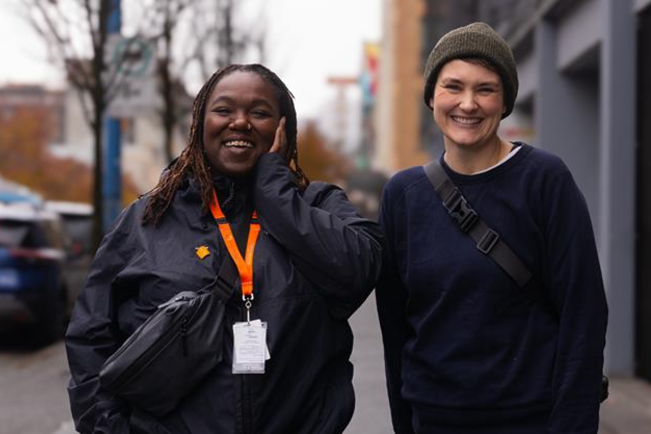 Two people posed smiling outside on a street