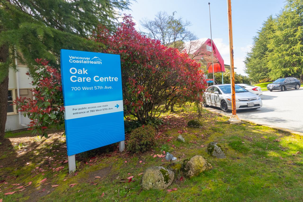 blue sign saying Oak Care Centre in front of bushes and trees with blue sky in the background