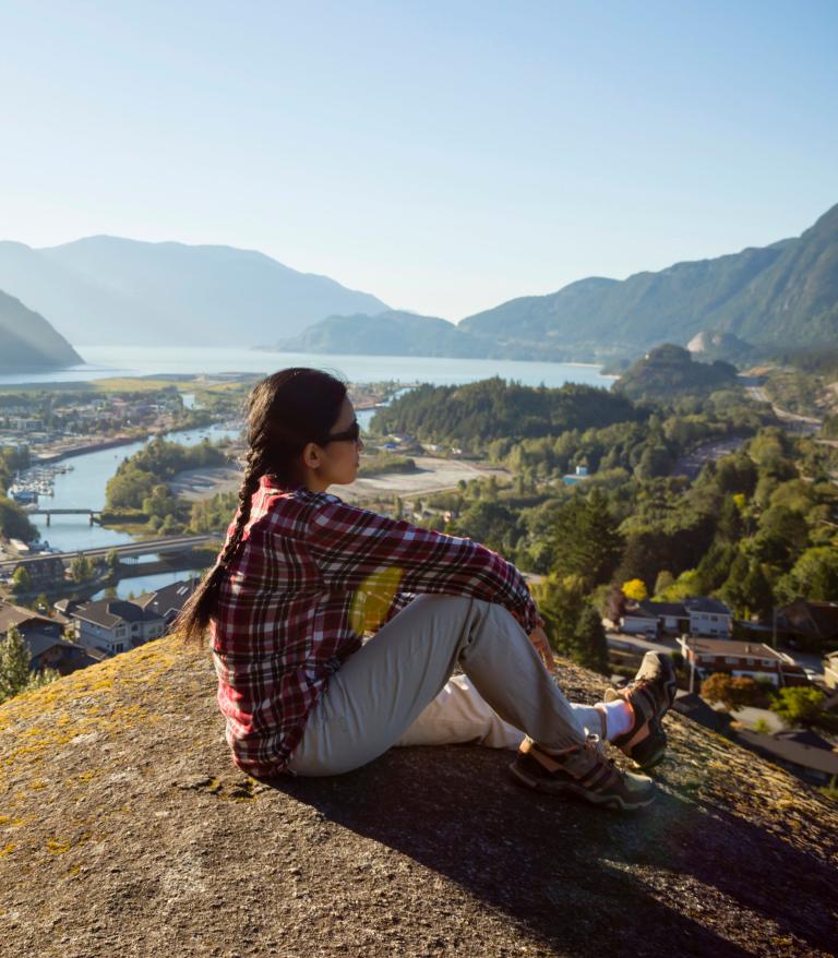 Person sitting on a rock in nature overlooking mountains