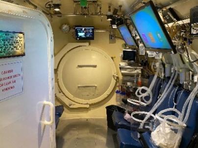 Inside of a Hyperbaric chamber with seats, tubes and screens on the walls
