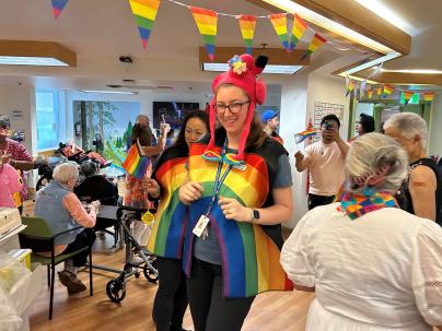 seniors and care workers dressed in pride colours celebrating in a large room