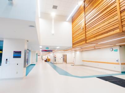A wide open hallway with wood paneling on one side in a hospital 