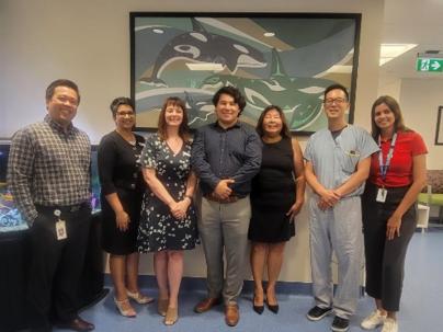 group photo with indigenous artist in front of artwork of whales