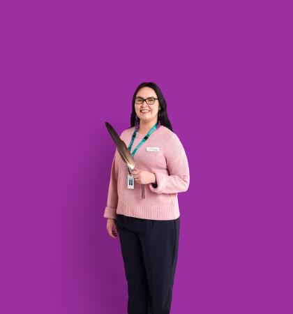Person holding a feather in front of a purple background