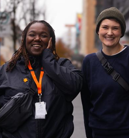 Two people posed smiling outside on a street