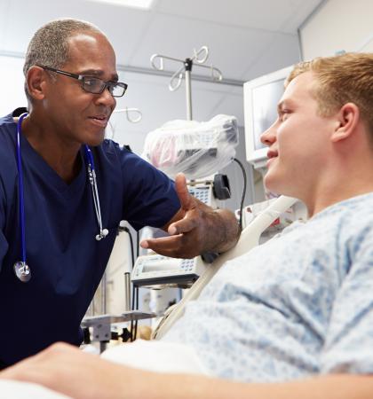 A doctor leaning over providing support to an adult in a hospital bed